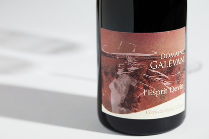 Close up label on a bottle of Galevan L Esprit Devin Cotes du Rhone Villages 2020 on a white table with shadows of the bottle and 2 wine glasses