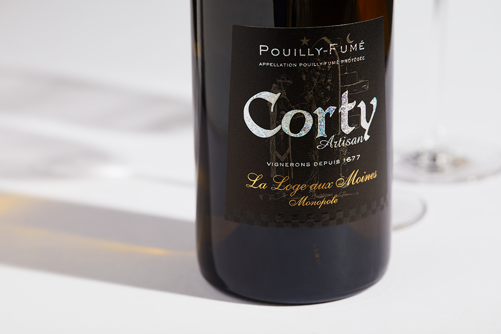 Close up label on a bottle of Moreux Corty Pouilly-Fume La Loge Aux Moines 2020 on a white table with shadows of the bottle and 2 wine glasses