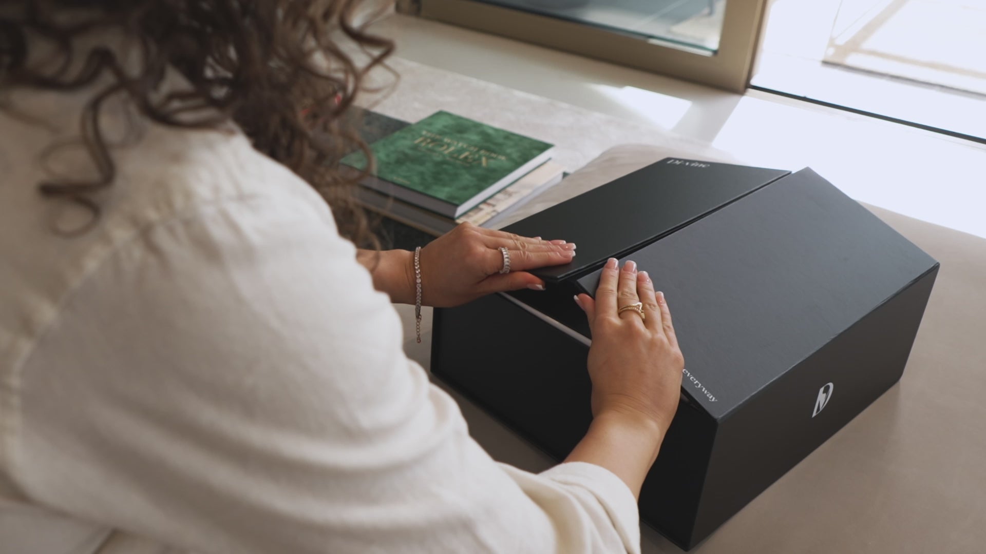 Short video of a woman opening the doors of a "Di-vine" elevator gift box, showing the inner box rising up and revealing the wines inside.