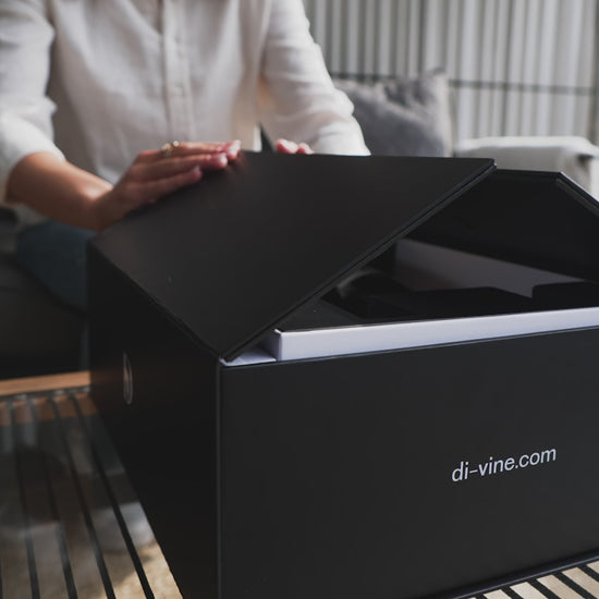 Short video of a woman opening the doors of a "Di-vine" elevator gift box, showing the inner box rising up and revealing the wines inside.