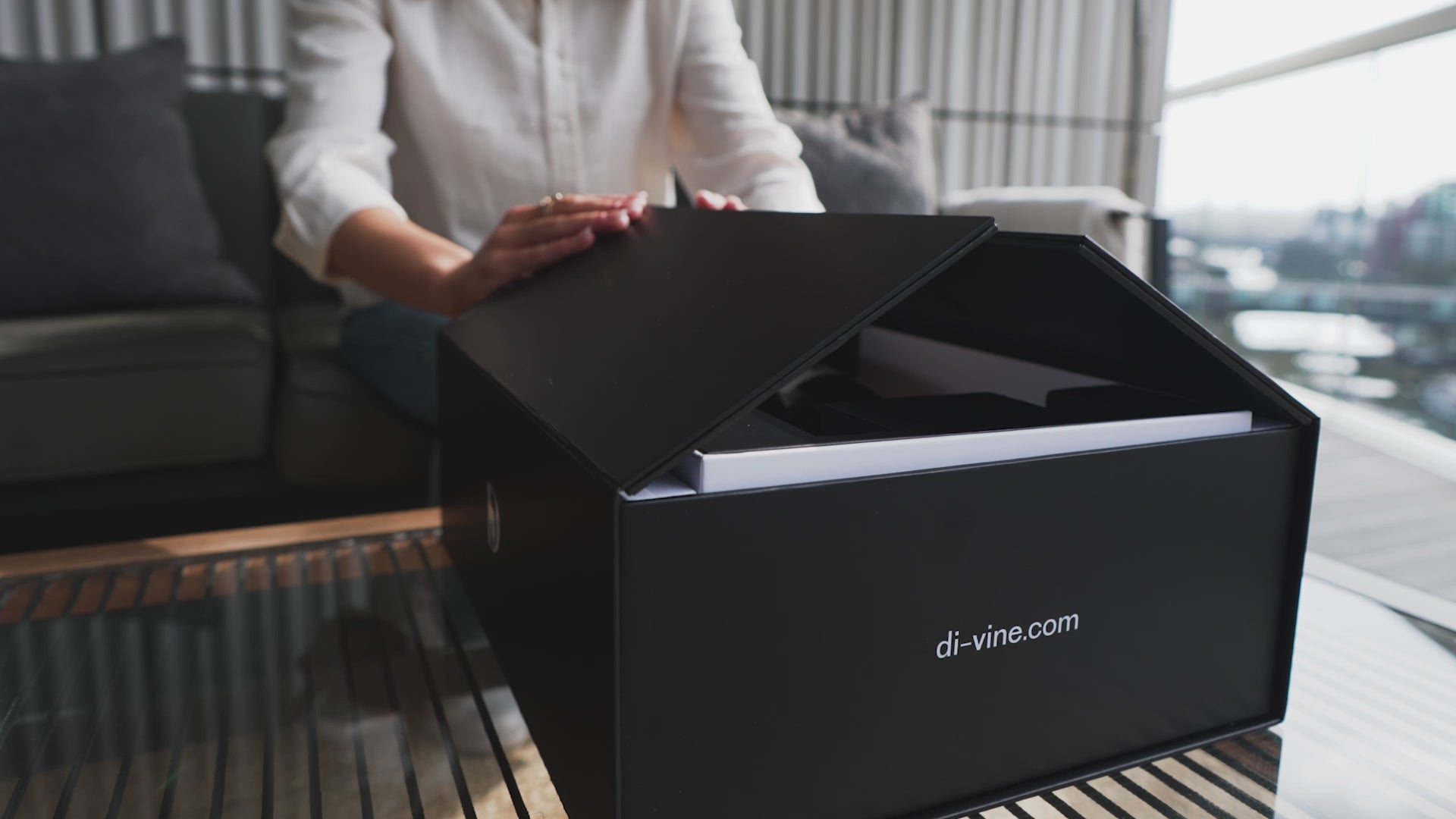 Short video of a woman opening the doors of a "Di-vine" elevator gift box, showing the inner box rising up and revealing the wines inside.