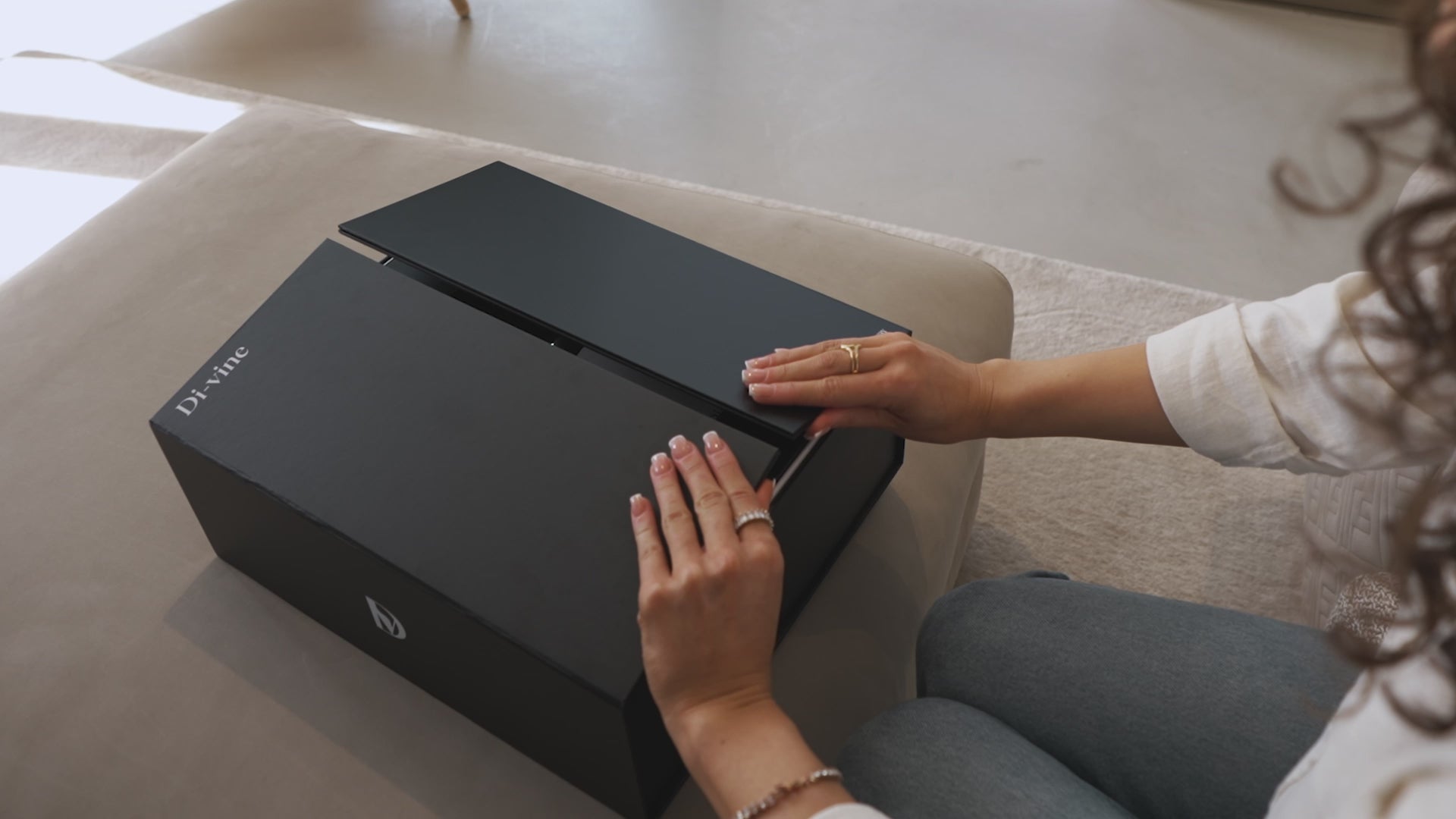 Video looking down on a woman’s hands opening the doors of a “Di-vine” elevator gift box and seeing a bottle of “Di-vine” red and a bottle if “Di-vine” white inside. 